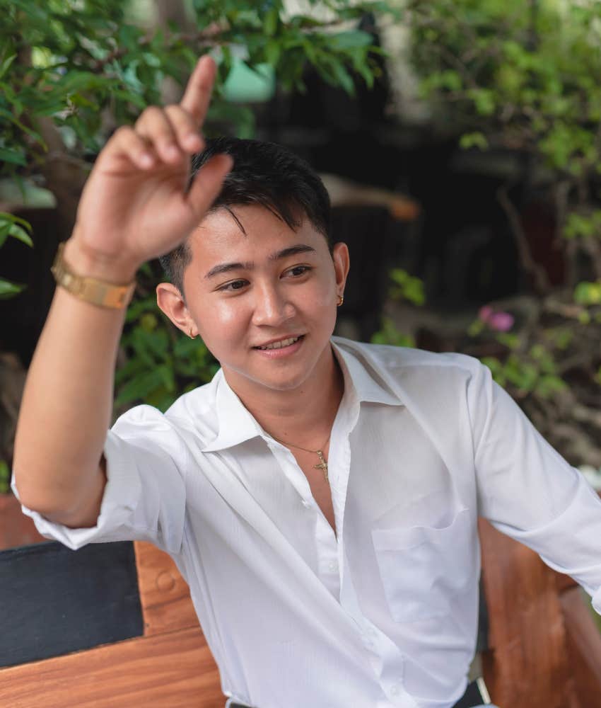 man raises finger to get attention showing he continues doing something