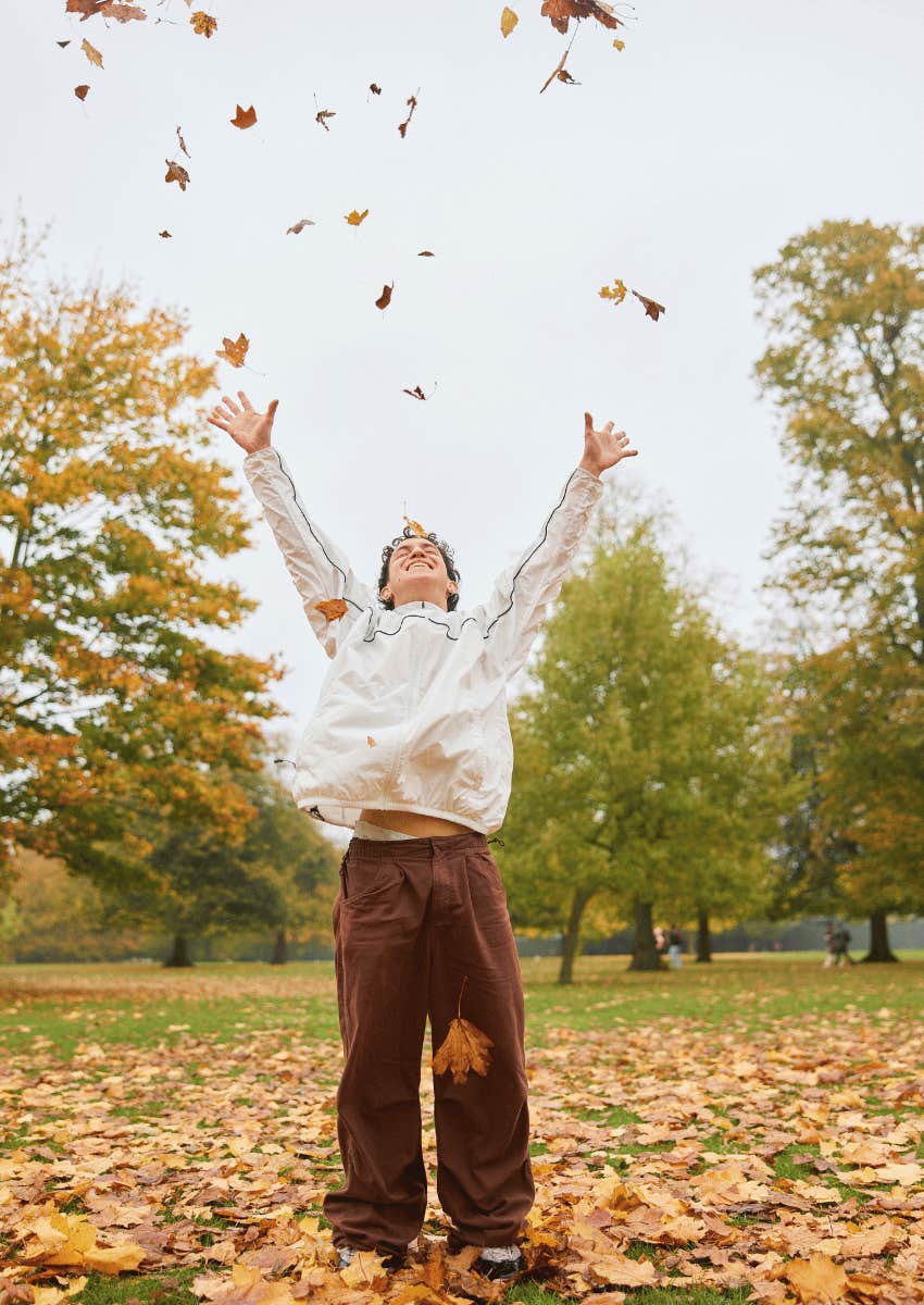 man throwing leaves into the air not looking for happiness