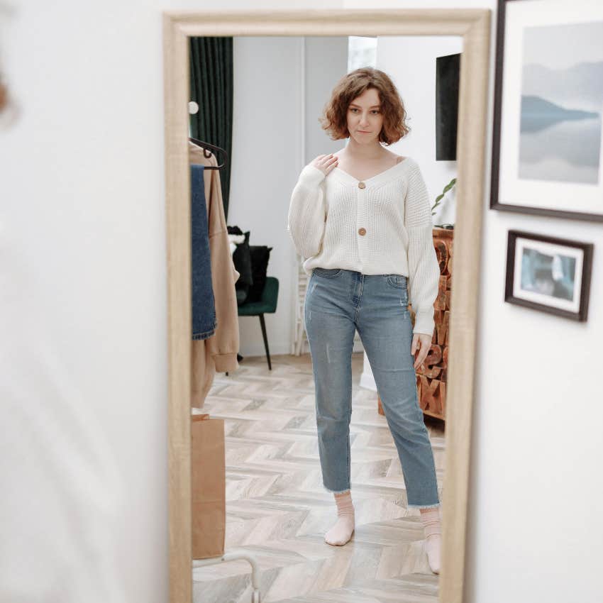 millennial woman looking at her outfit in the mirror