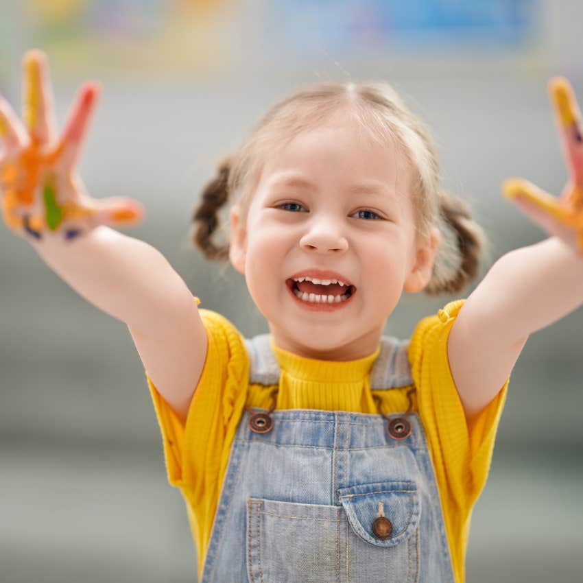 little girl holding up paint-covered hands
