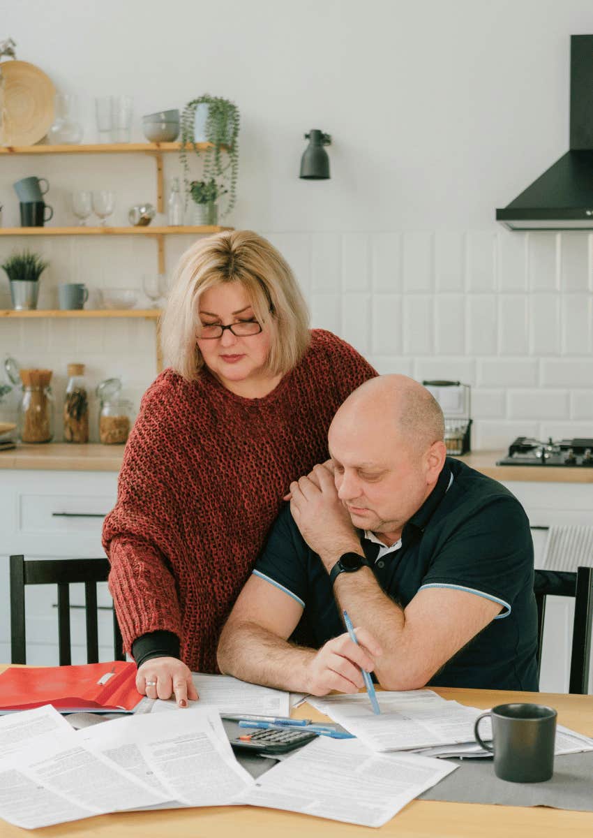 older couple sitting close at kitchen table working together