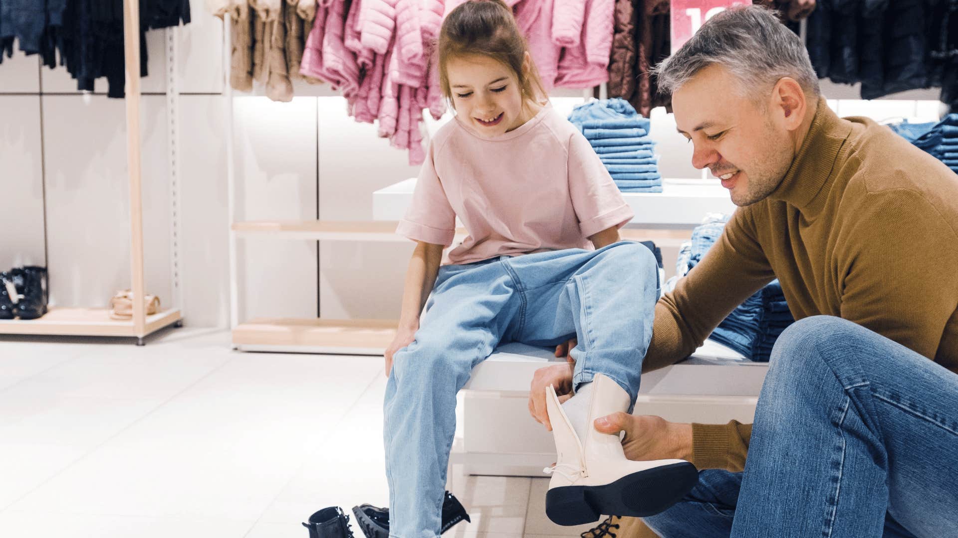 dad helping daughter try on shoes telling her not to worry about the price