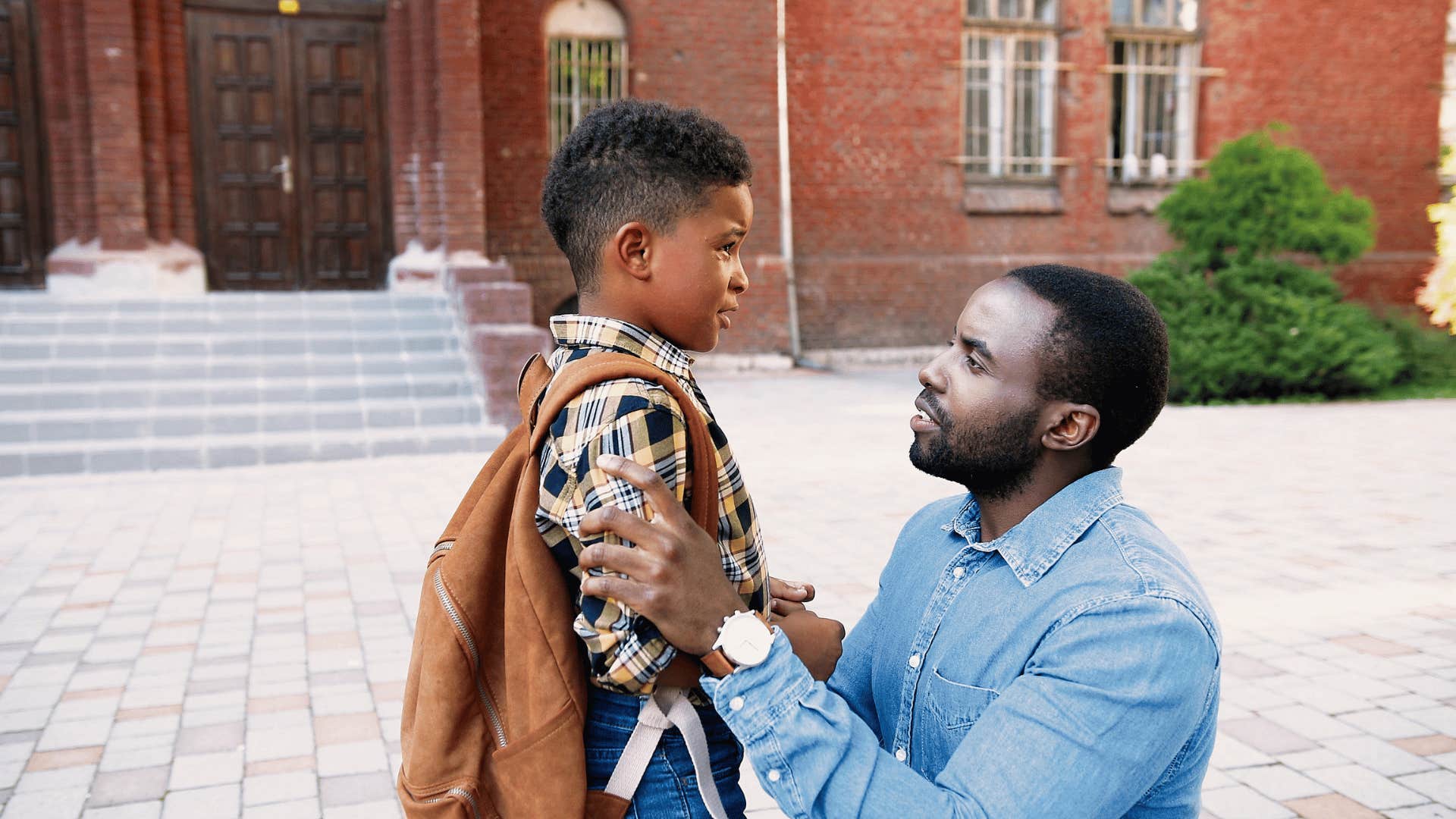 dad kneeling down talking to son at school saying you don't have to share