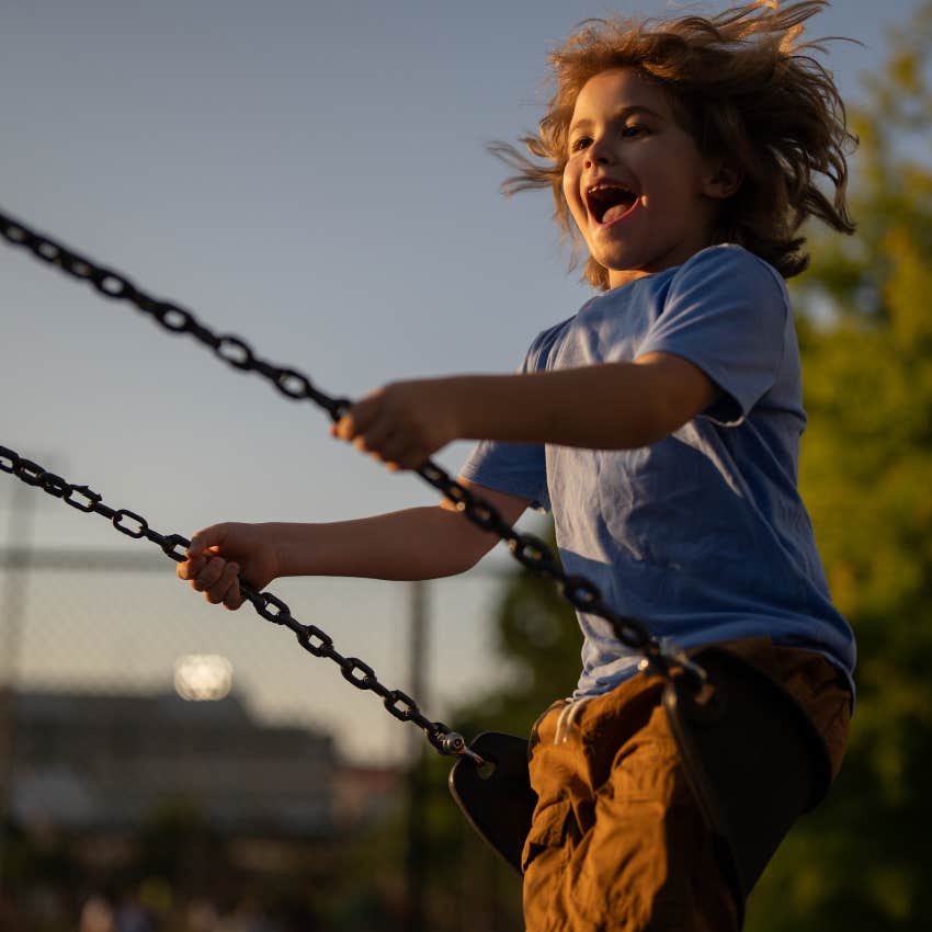 little boy swinging on swing at park