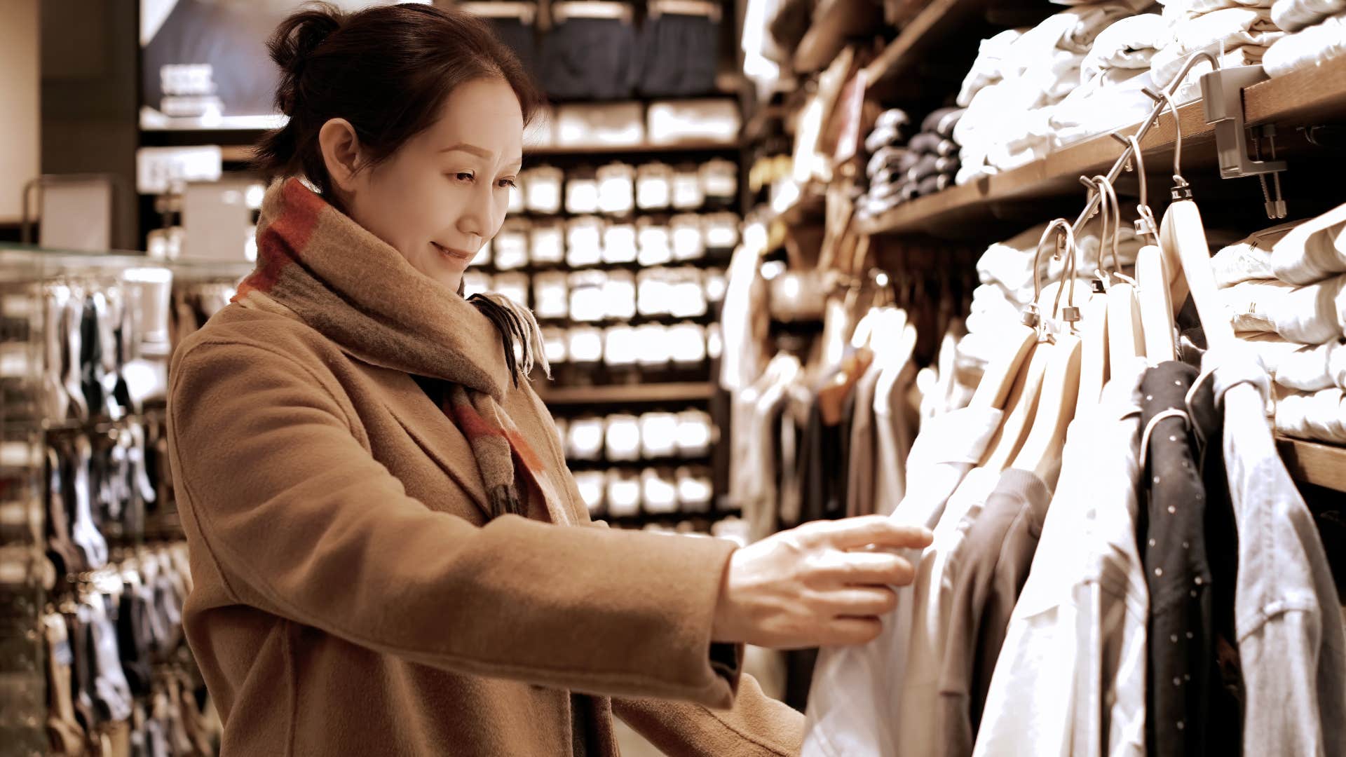 Woman shopping in person at a clothing store.