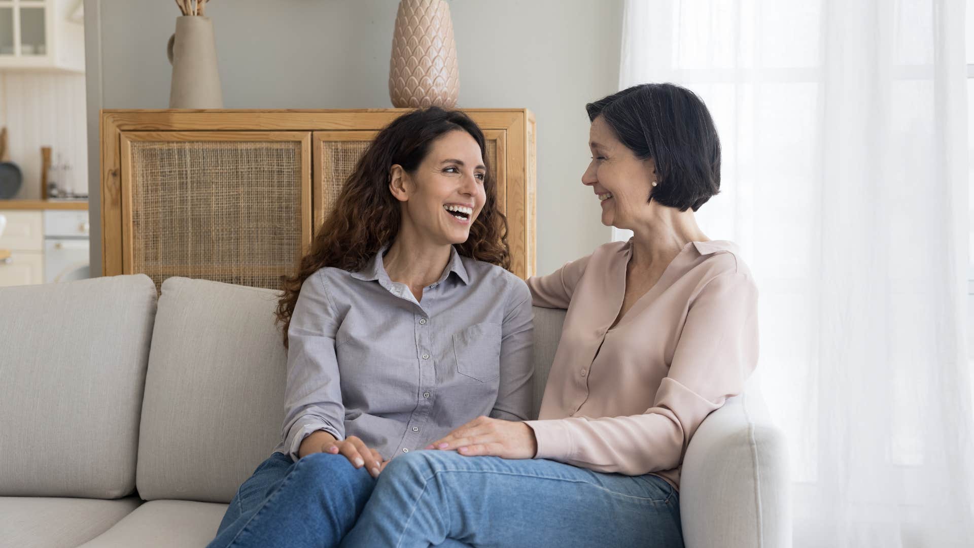 two women talking and laughing on couch