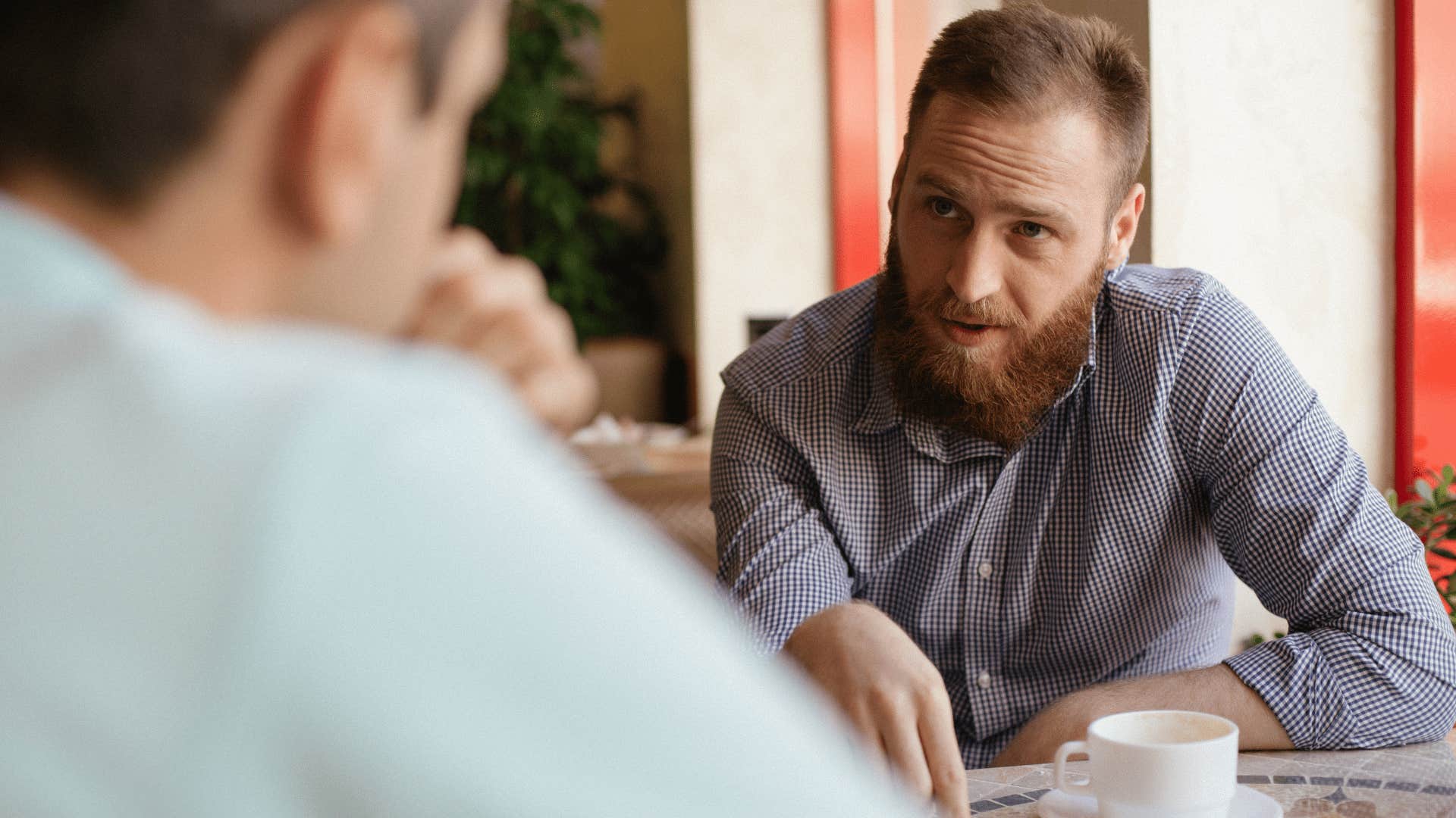 intelligent man asking friend why does that work during discussion at cafe
