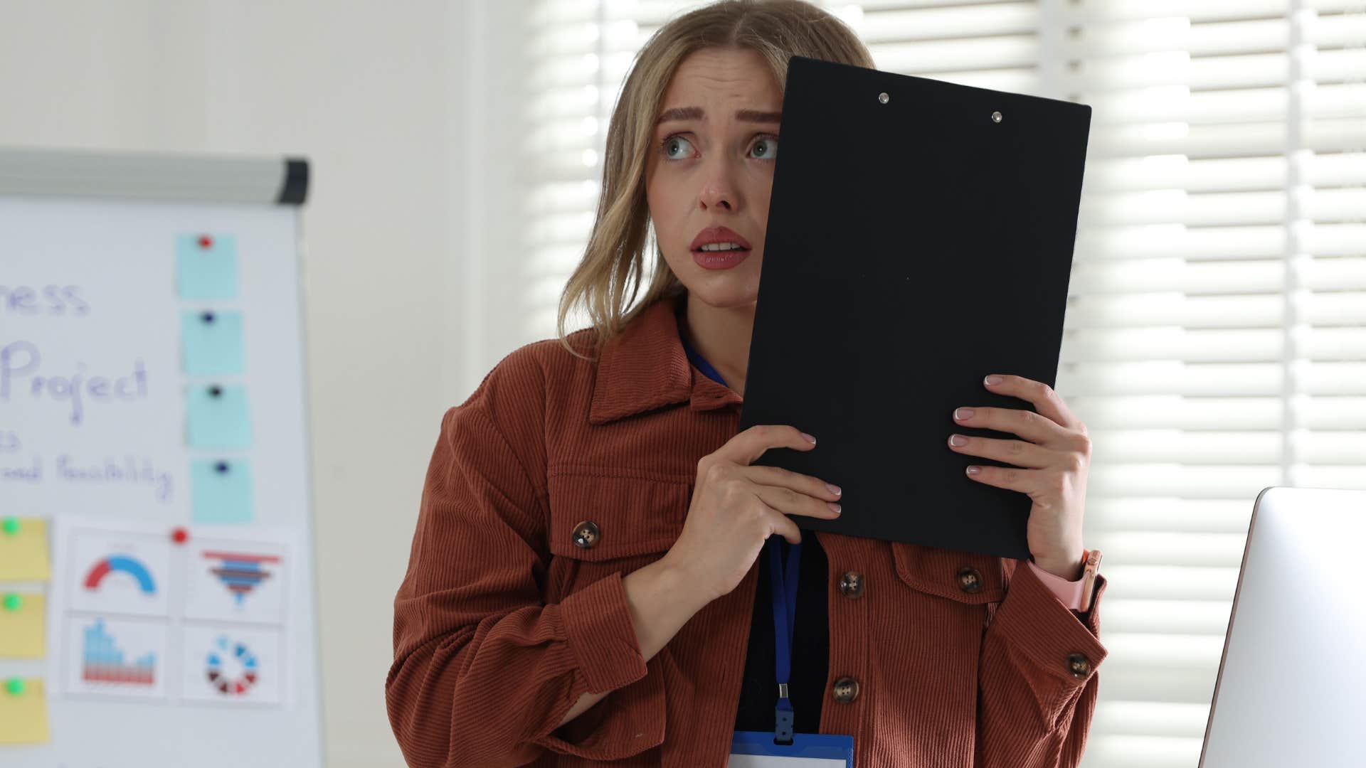 woman hiding behind clipboard ignoring someone in group settings at work