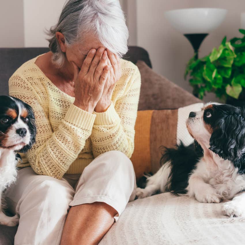 Elderly woman sitting alone at home crying with her two dogs