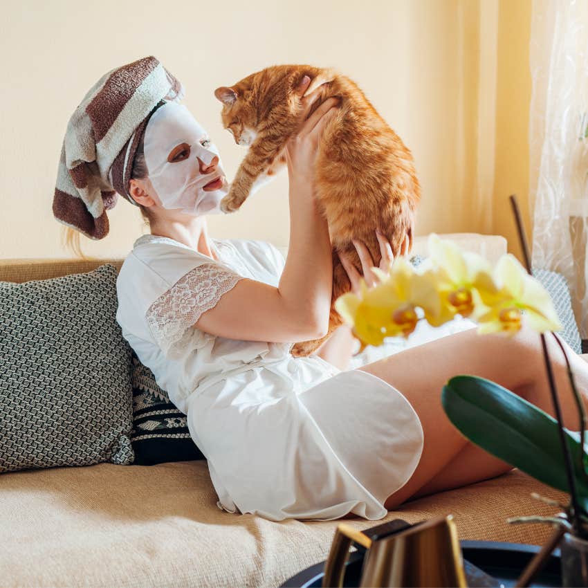 Woman sitting on the couch with her cat relaxed with a face mask on