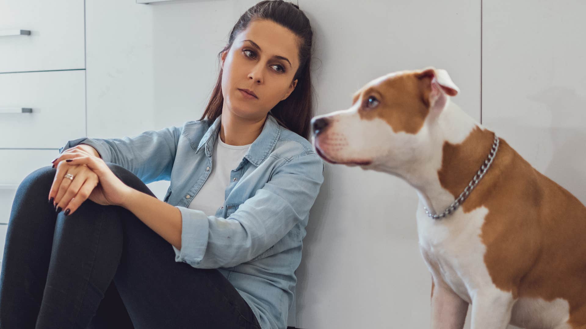 woman punishing her dog sitting in the kitchen together