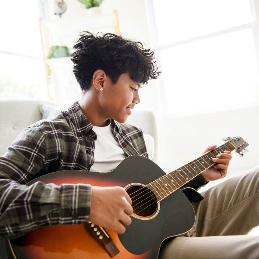 teenage boy playing guitar at home