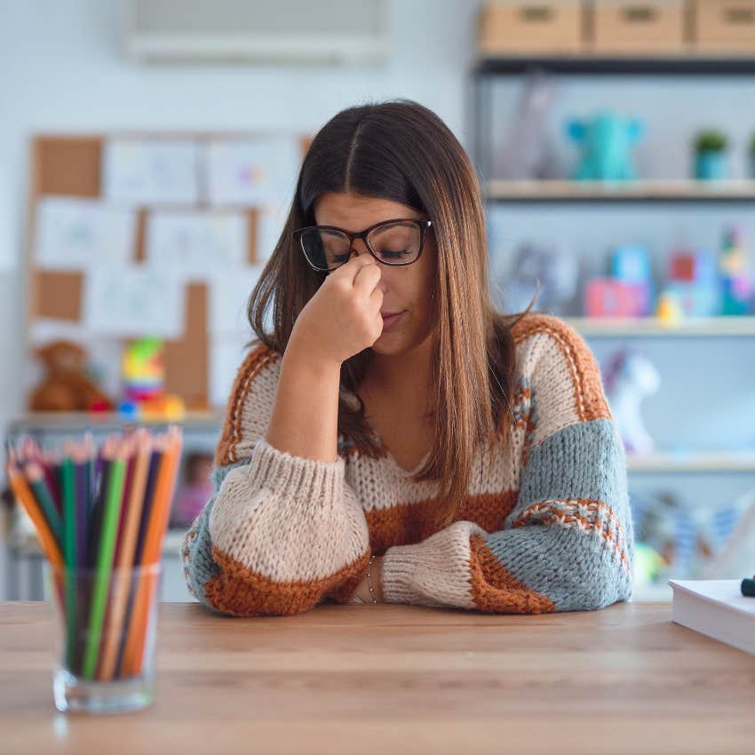 stressed teacher sitting at desk in classroom quits to become professional cuddler