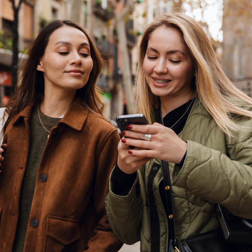 two friends looking at phone being distracted in shared space