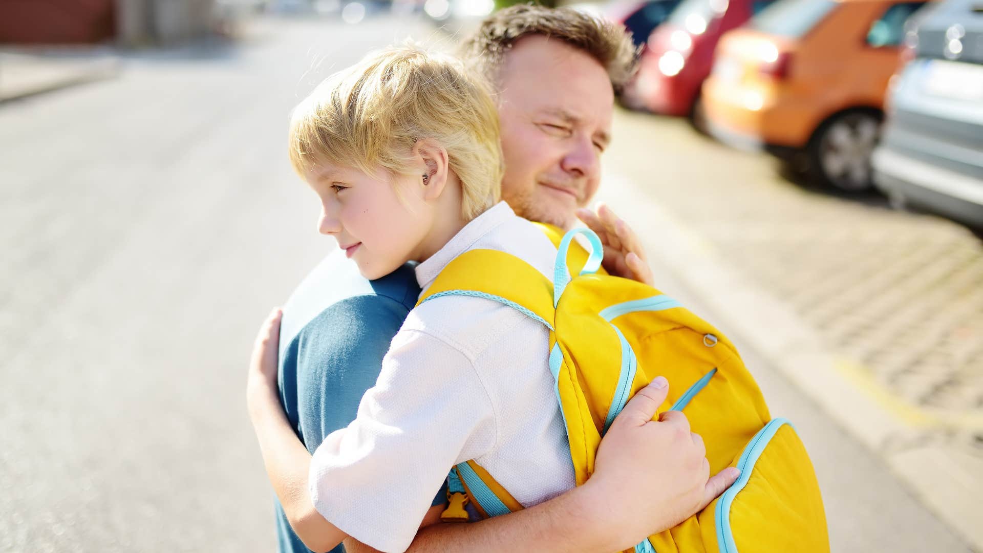 father encouraging and hugging son while dropping him off at school