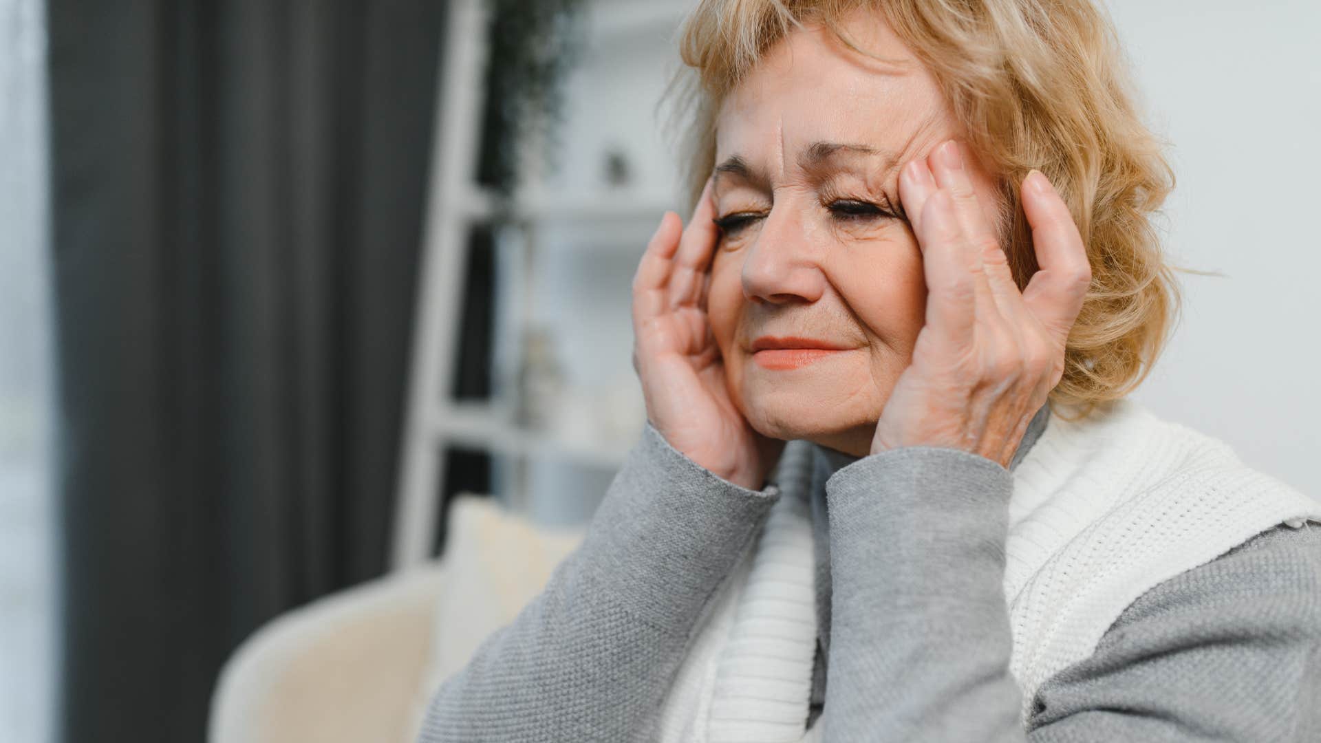 retired older woman rubbing her temples feeling tired