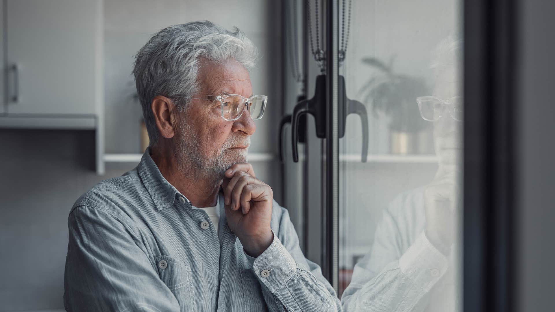 retired boomer man looking out window not enjoying endless relaxation