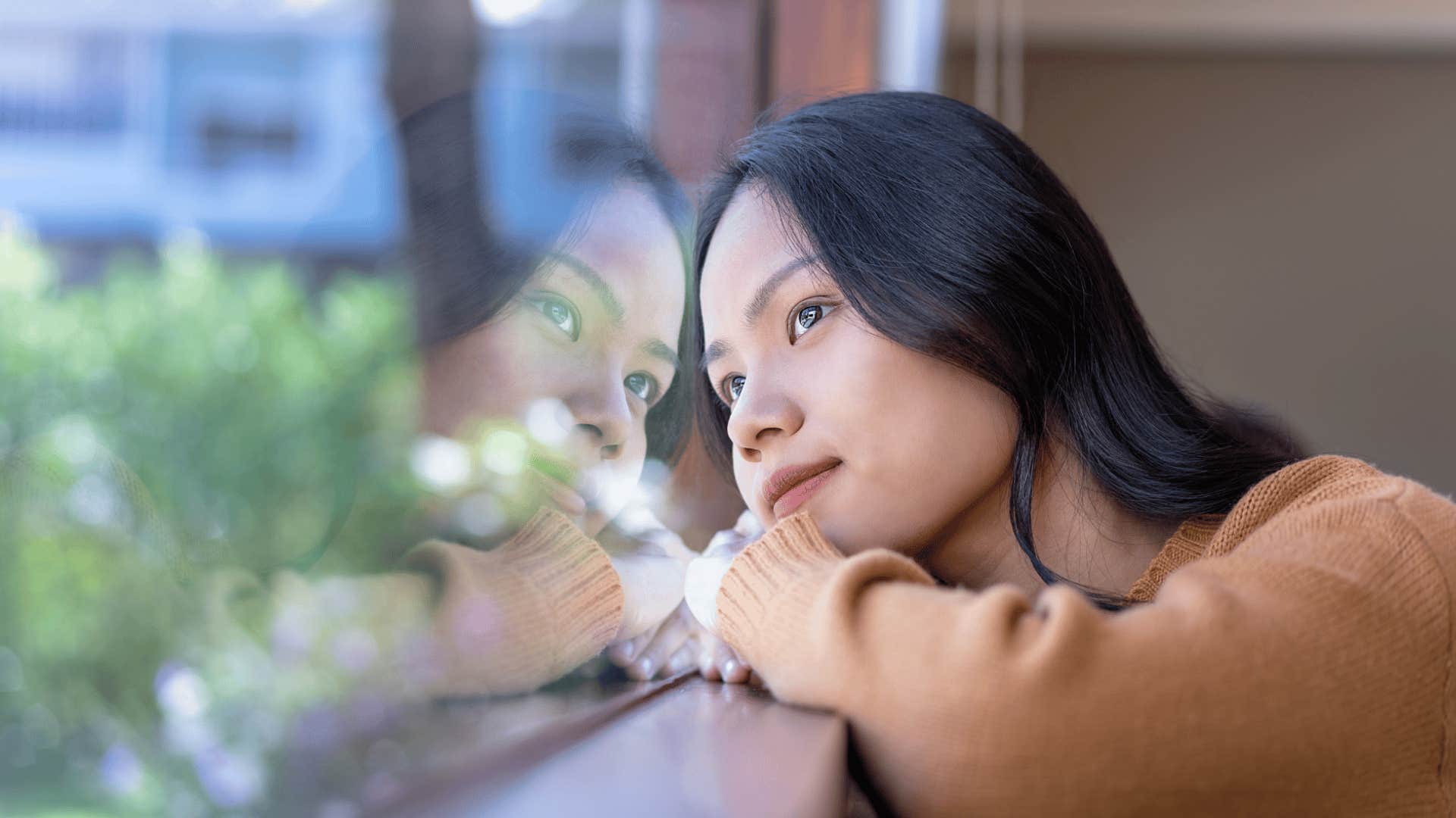 Woman daydreaming out a window away from her spouse 