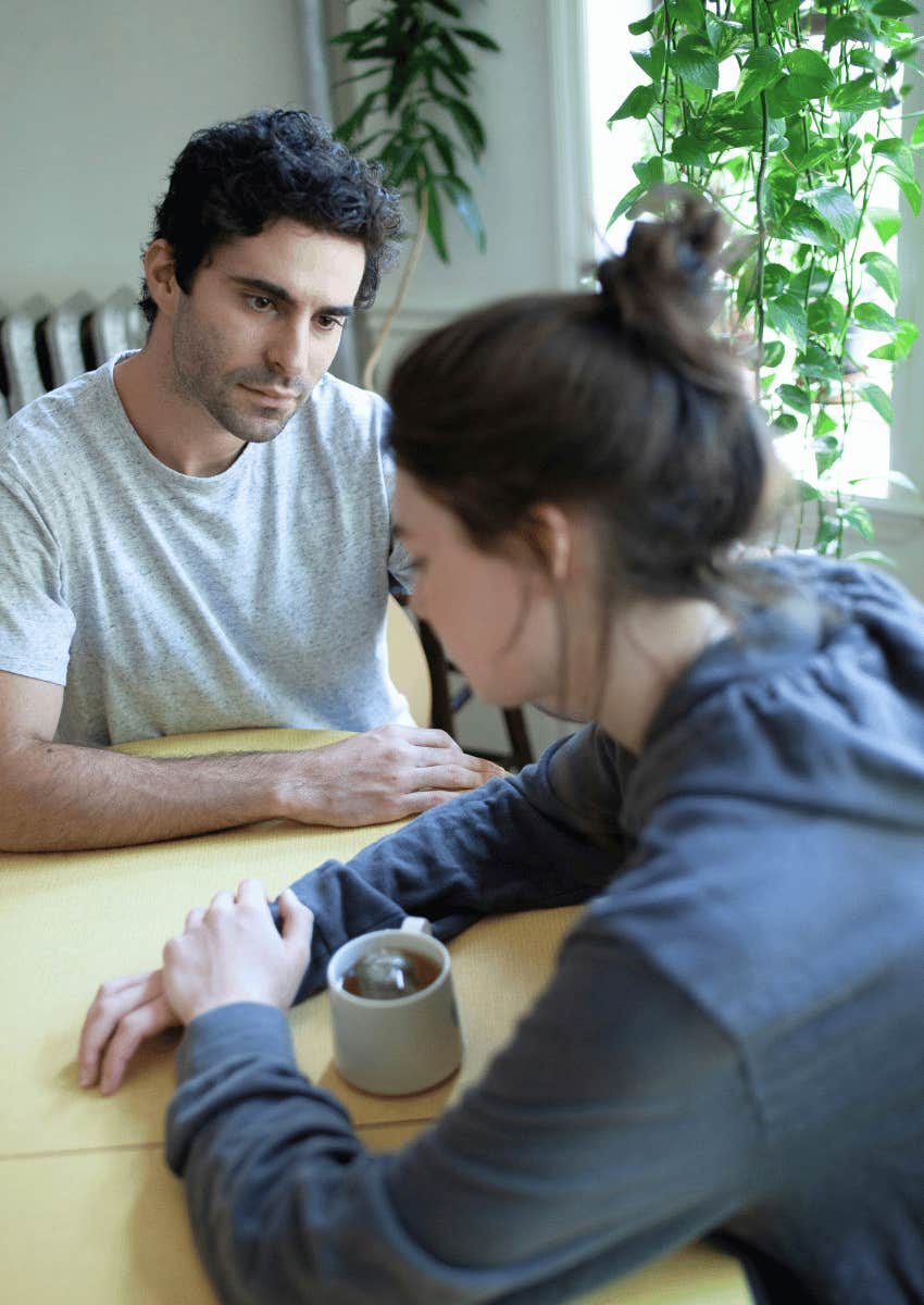 serious man staring at apologizing woman