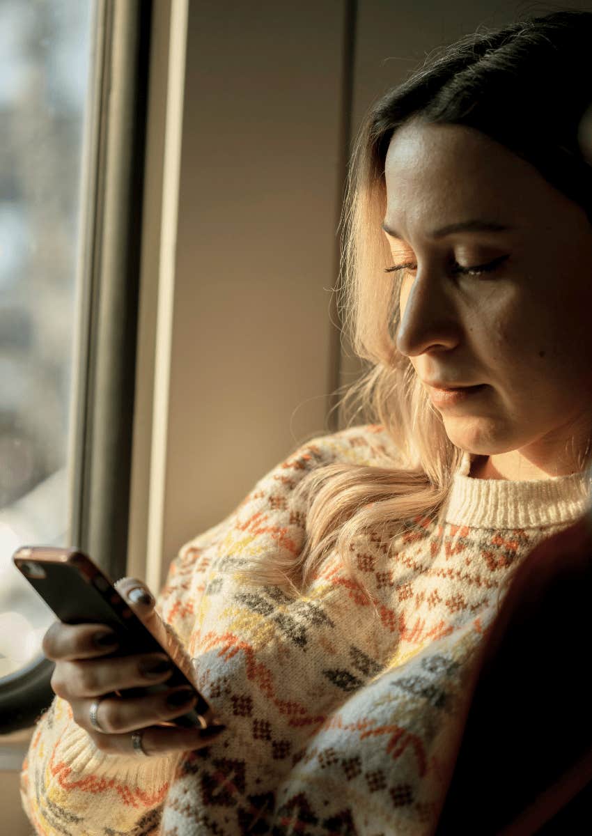 serious woman looking down at her phone
