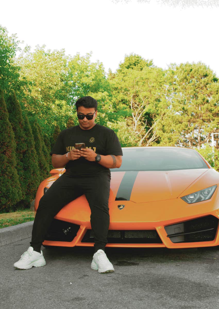 shallow man sitting against flashy car