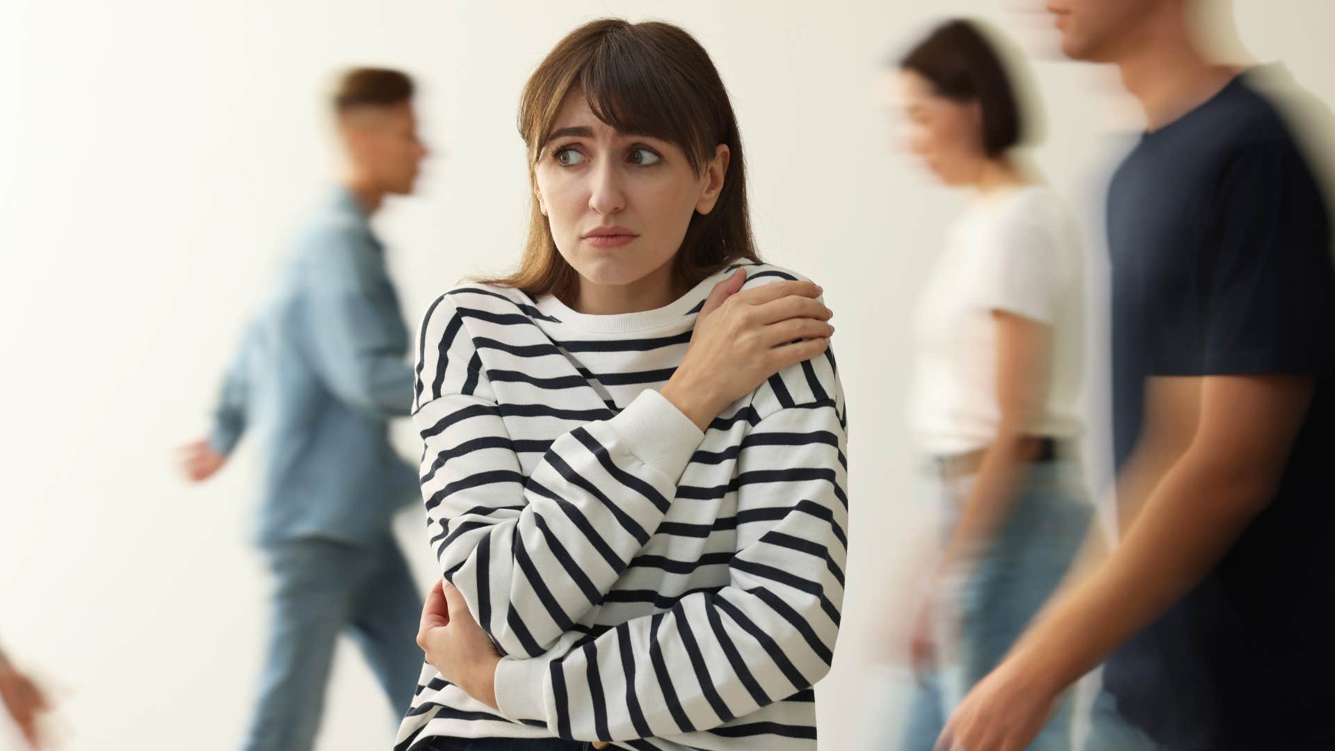 Woman looking afraid in a busy room while overwhelmed by emotions 
