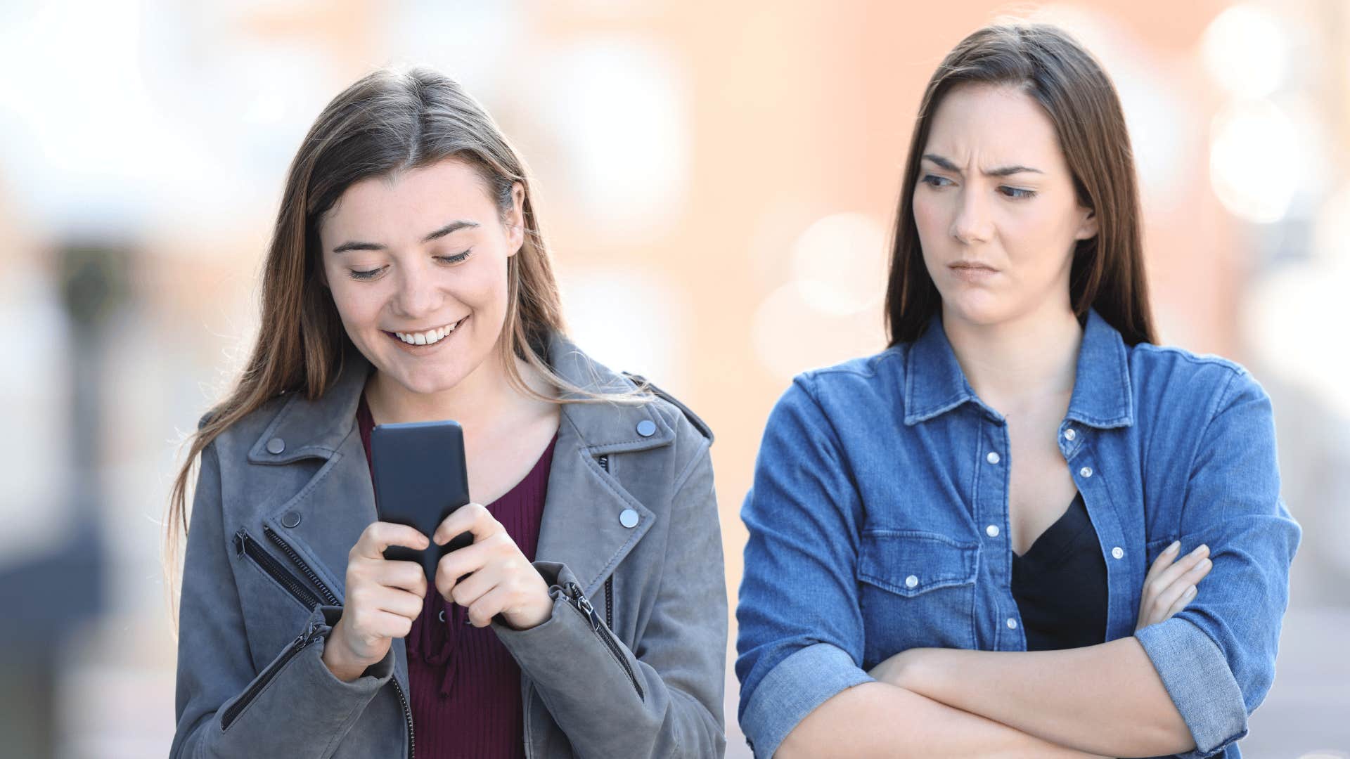 woman looking at her friend texting becoming distant