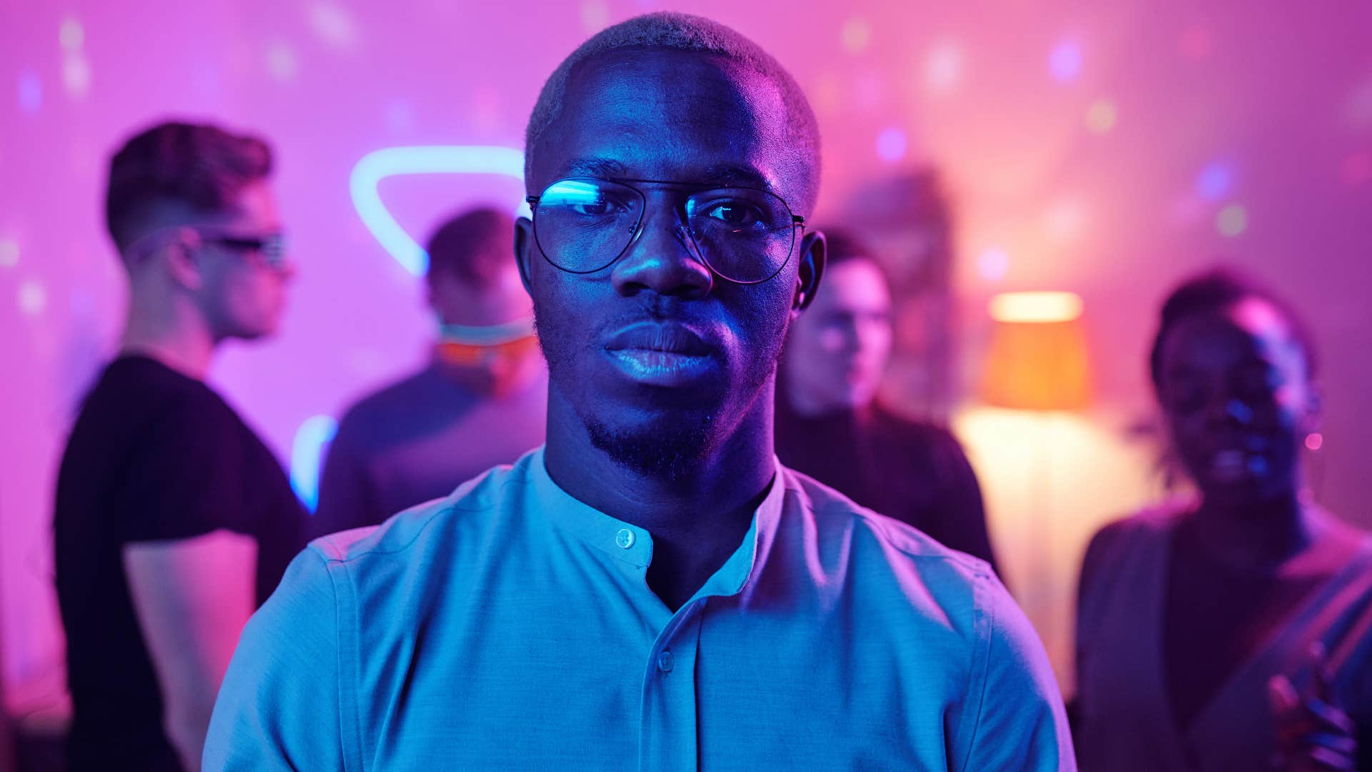 Lonely man looking serious in a dance club with happy people 