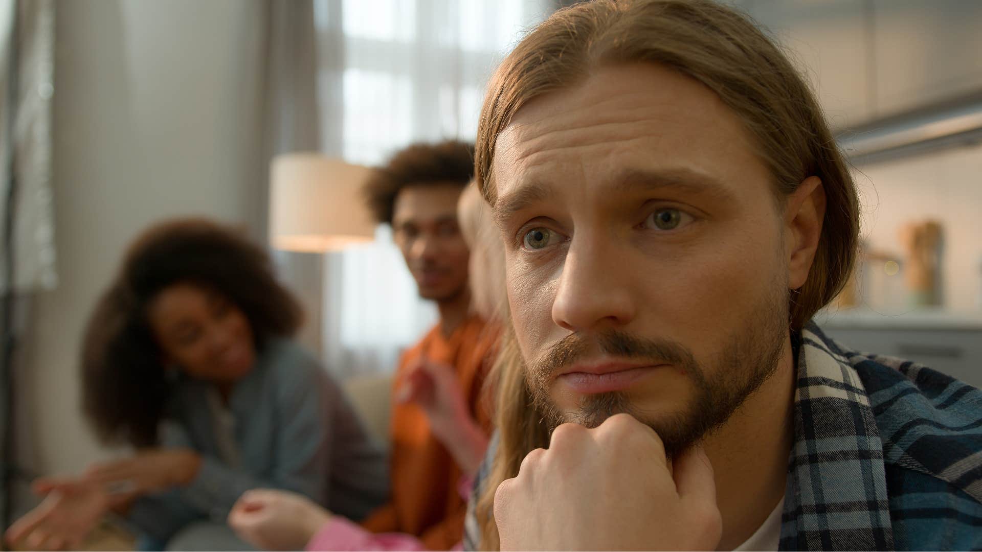 Lonely man looks sad even with friends around