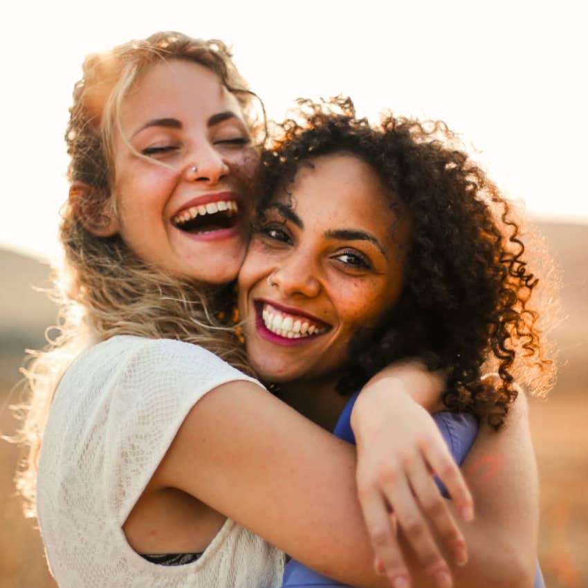 Two women BFFs who will be best friends forever hugging in a field happily