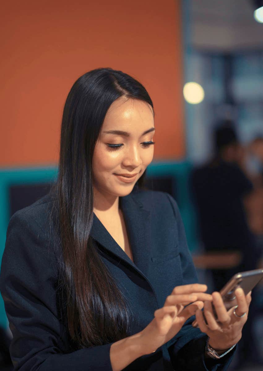 sly woman smiling down at her phone