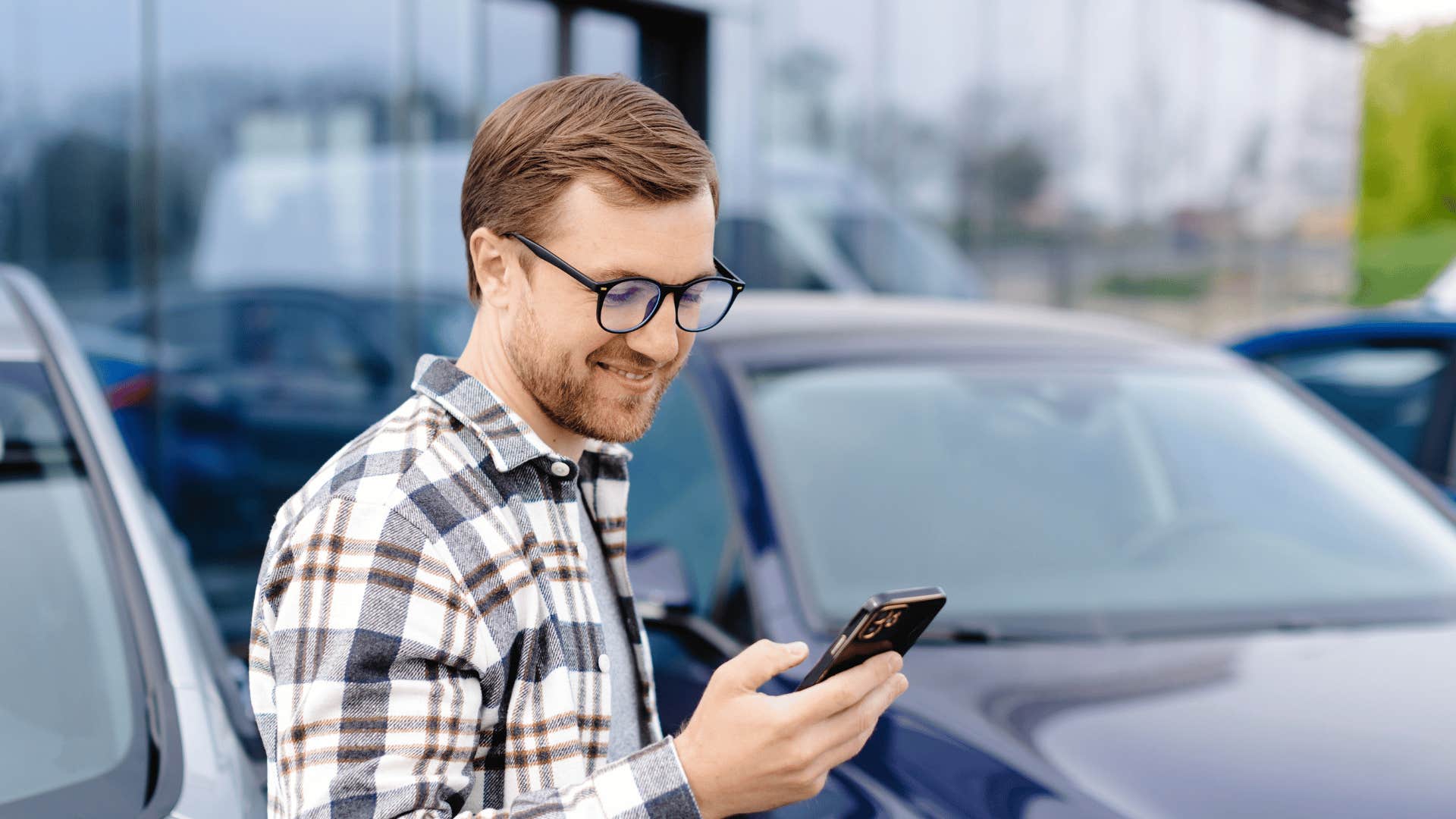 man looking at phone as buying new car gadgets
