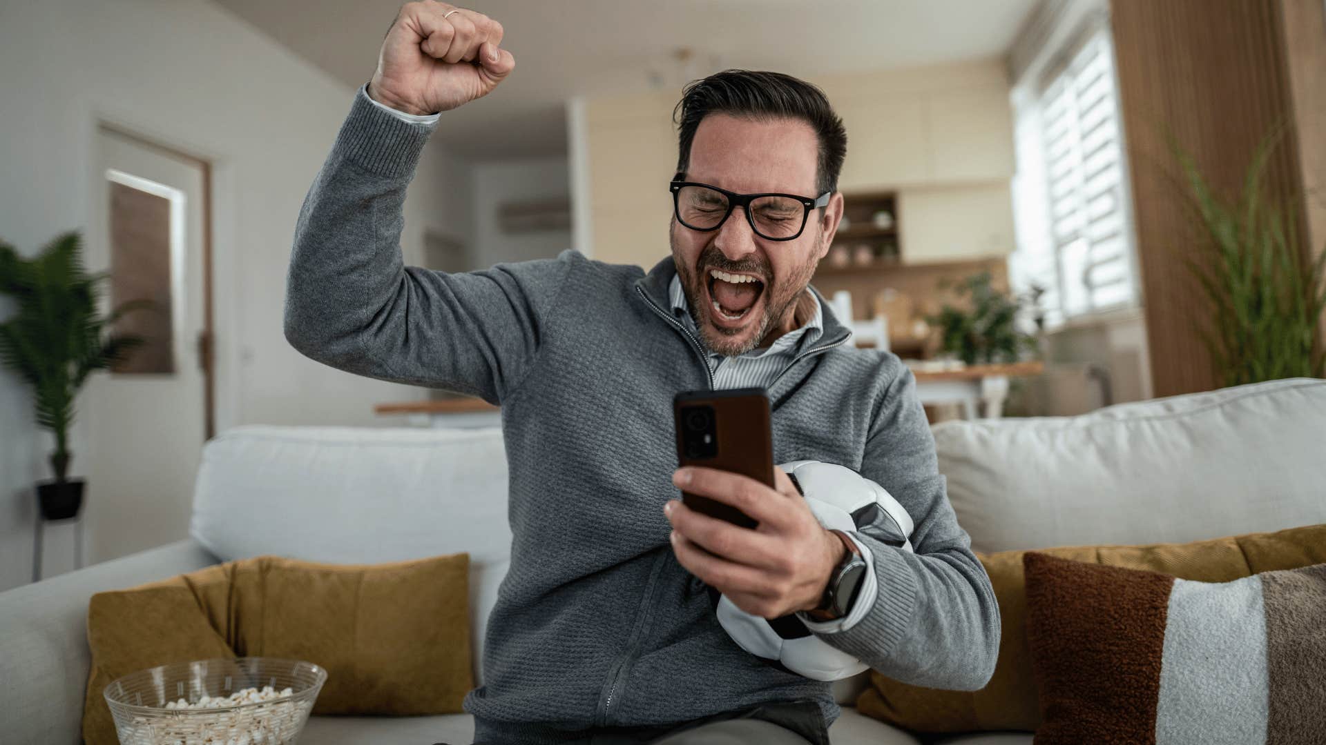 man excited engaging in sport betting on his phone