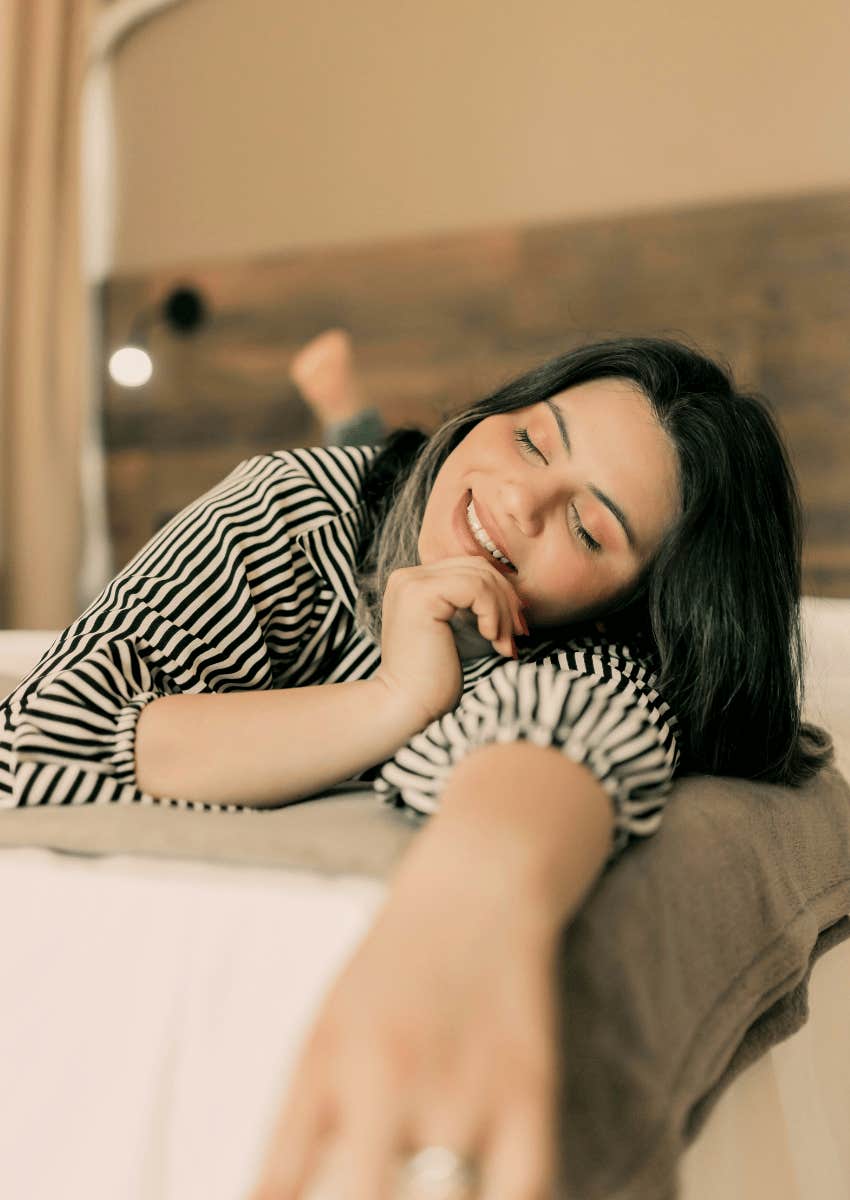 smiling woman relaxing in bed alone