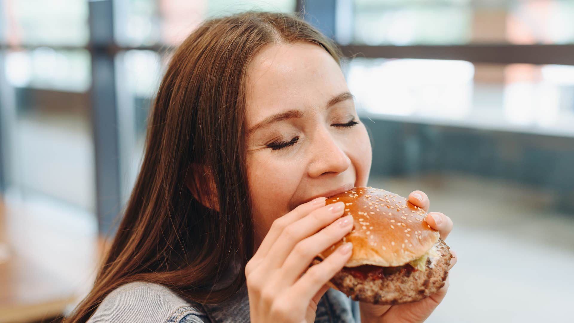 woman biting into a huge hamburger