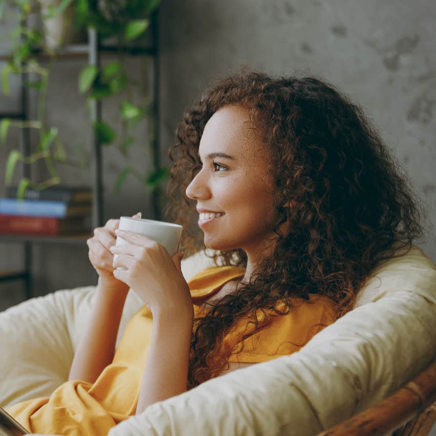 smiling woman drinking coffee and enjoying alone time