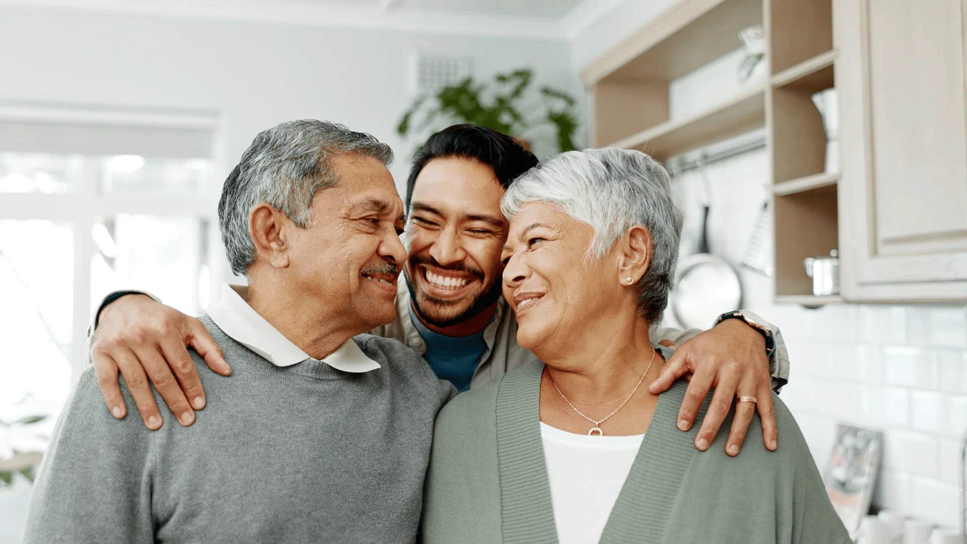 adult son hugging older parents believing love alone keeps a marriage strong