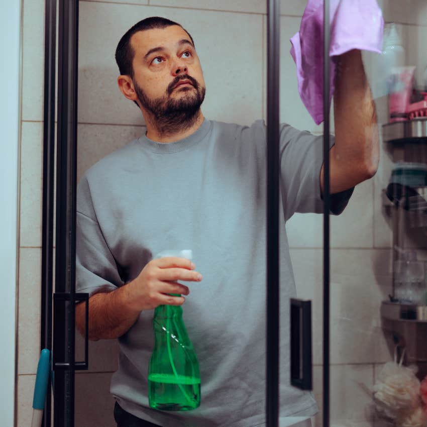 serious man cleaning shower at does extra household tasks because grew up as cinderella 