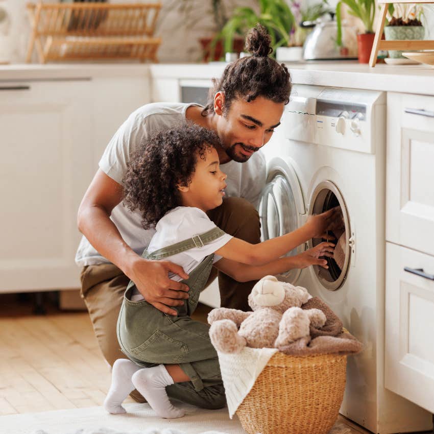dad and son putting laundry into washing machine doing chores together