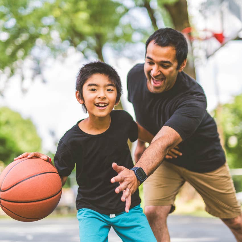 dad and son playing basketball in the park on saturday morning