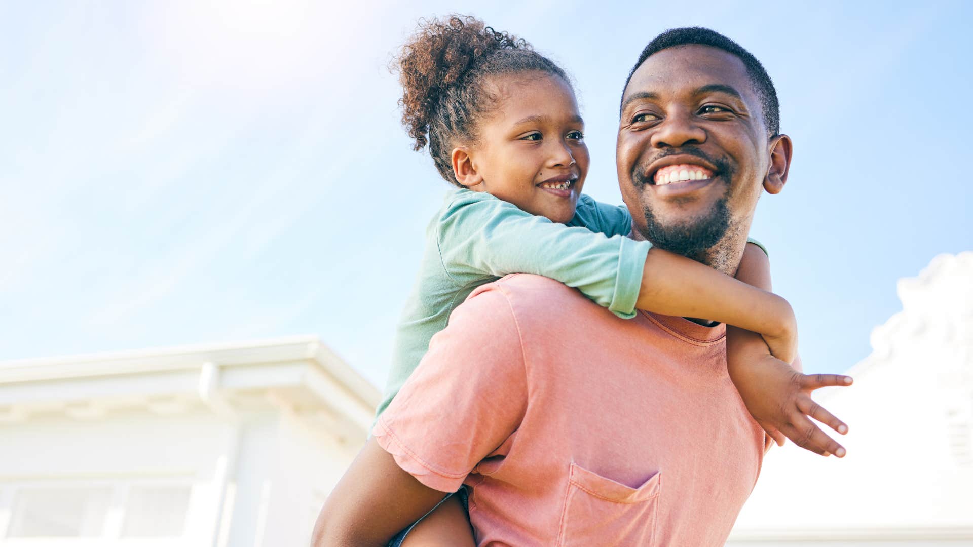good man who is a present father giving daughter a piggy back ride