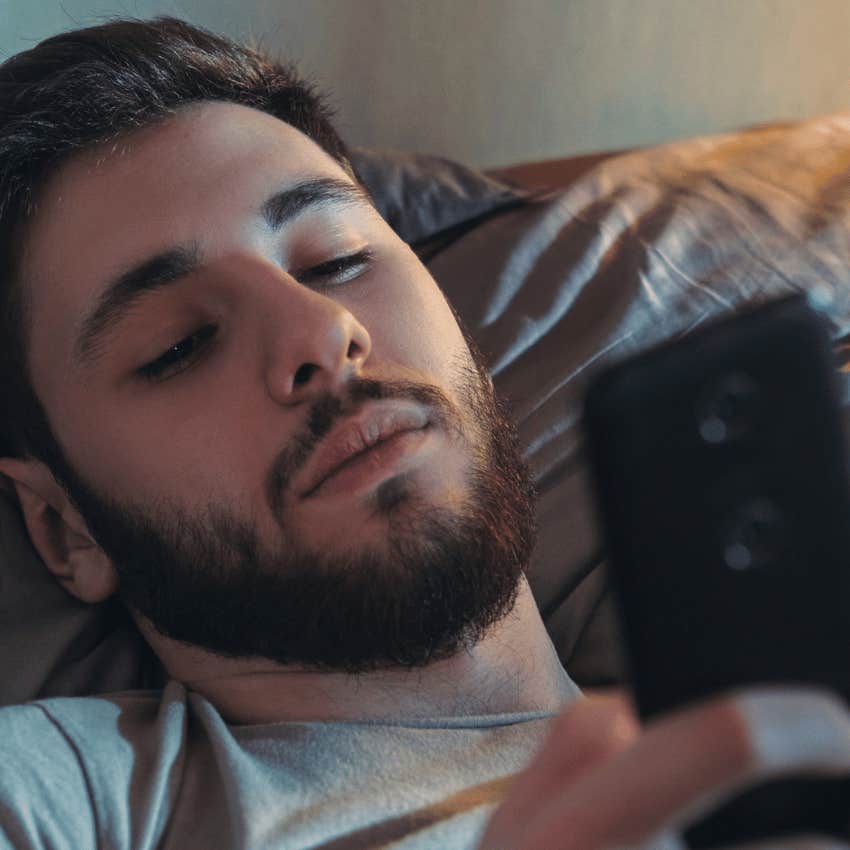 miserable man scrolling on his phone from bed in the morning