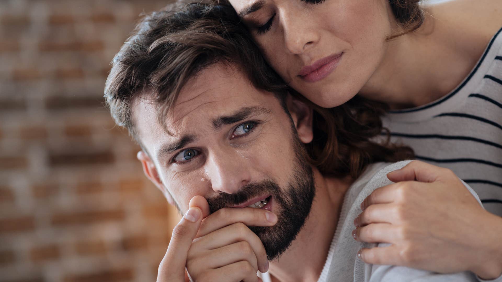 man struggling to manage his emotions being comforted