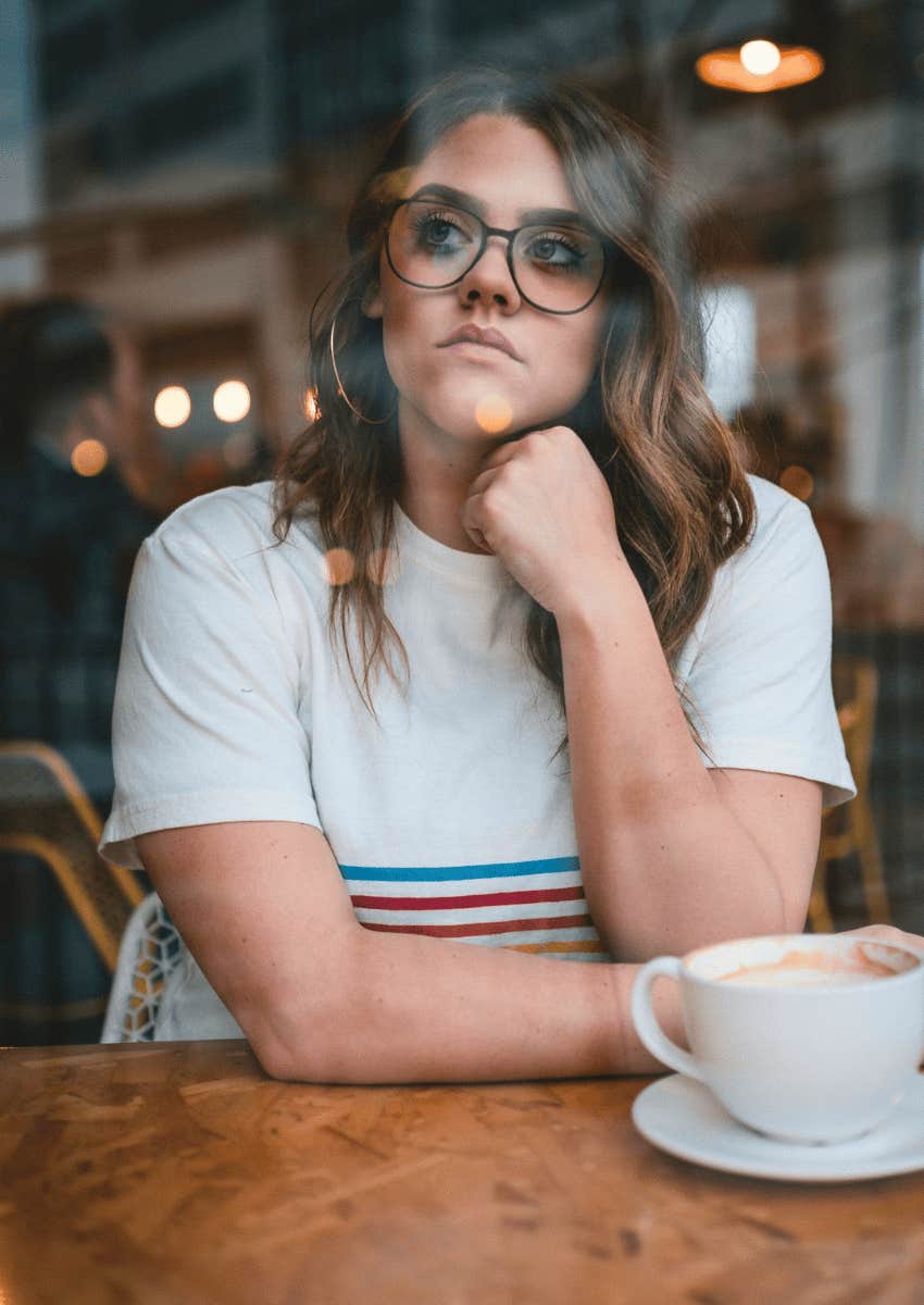 thoughtful woman sitting alone at a coffee shop