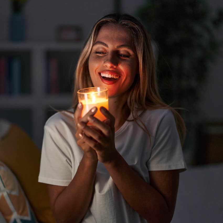 smiling female witch using candle for a transmutation spell when someone is talking bad about her