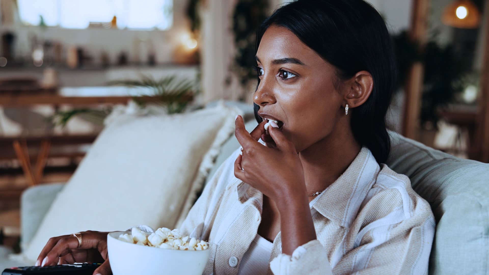 woman watching boring movies at home eating popcorn
