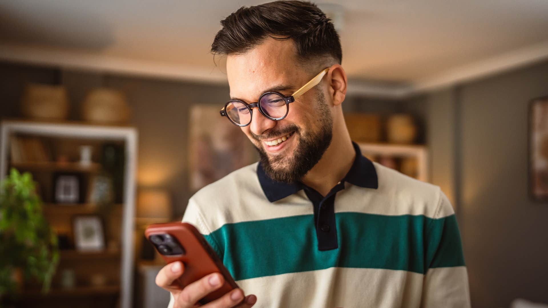 introverted man smiling at last-minute canceled plans on his phone