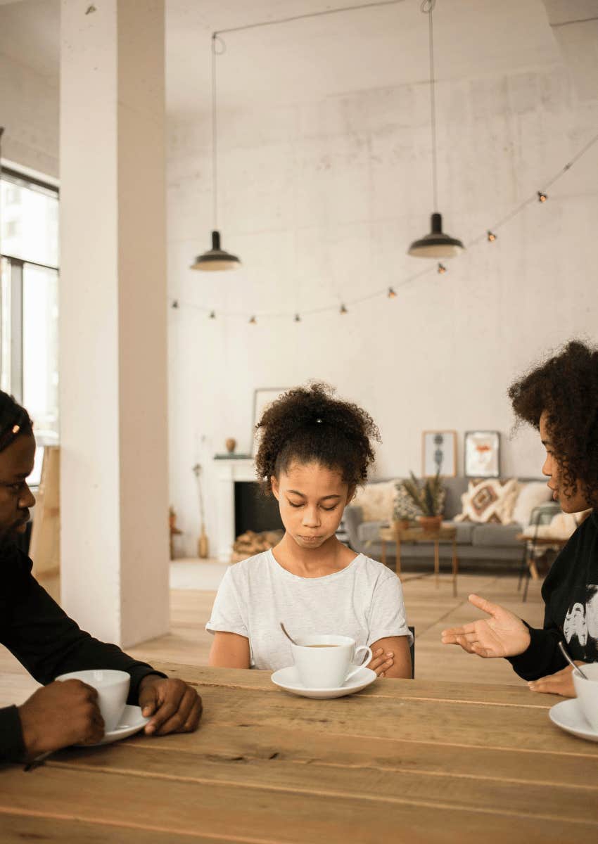unhappy child sitting in between parents