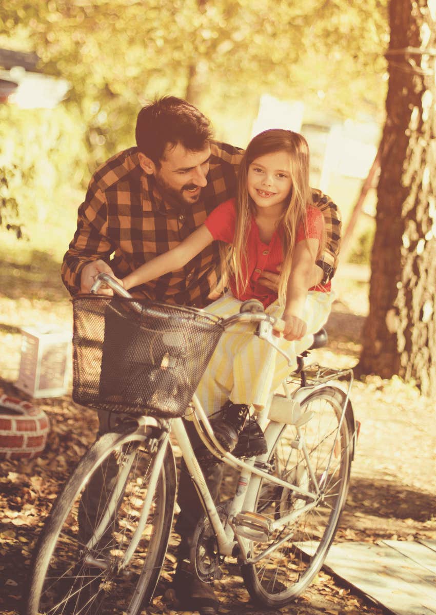 vintage photo of adult man helping child ride bike