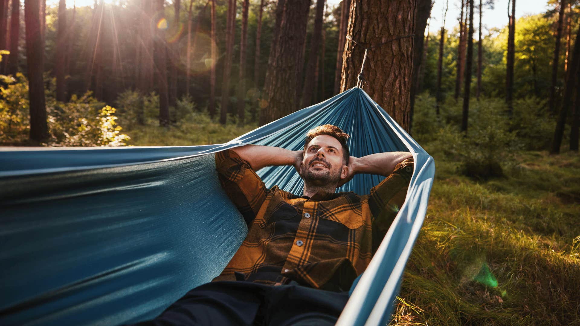 man getting outside for self-preservation laying in hammock in the woods